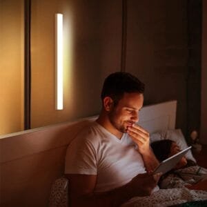 Lámpara LED recargable de 30 cm con sensor – Uso nocturno cómodo y seguro Hombre leyendo de noche iluminado por lámpara LED recargable de 30 cm instalada en la pared